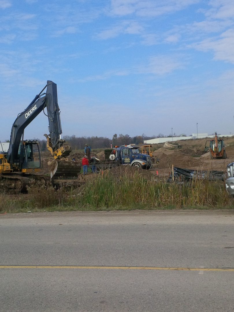 A large construction site with several vehicles parked on the side of it.