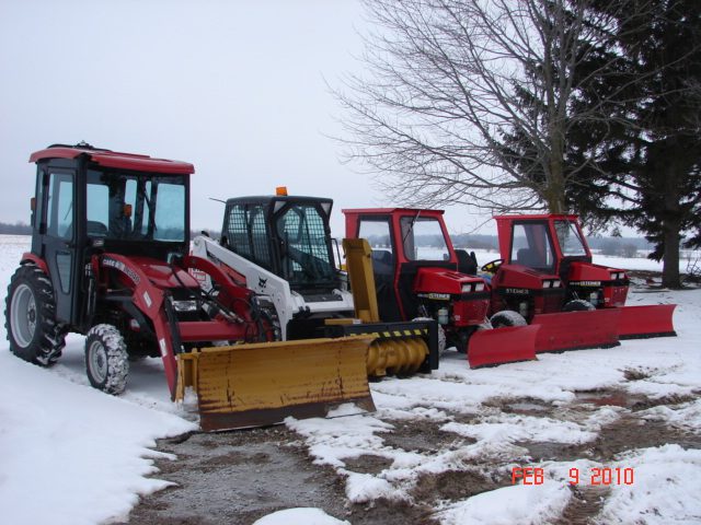 A group of tractors parked in the snow.