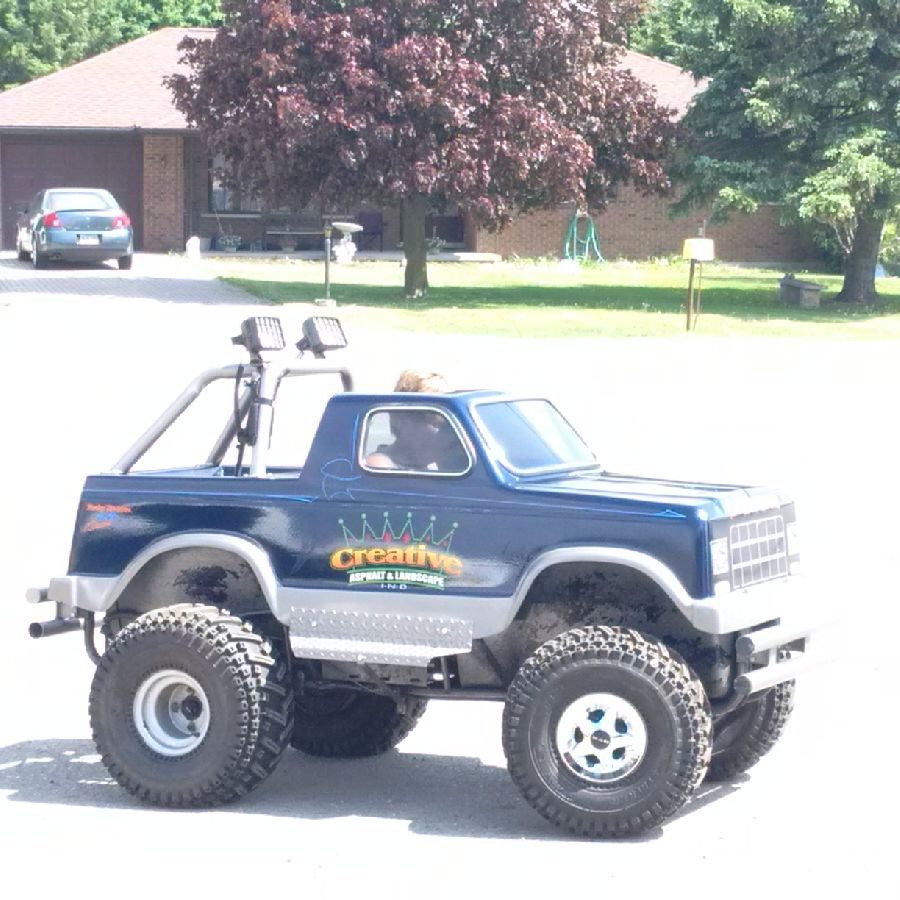 A blue truck with a large tire on the back.