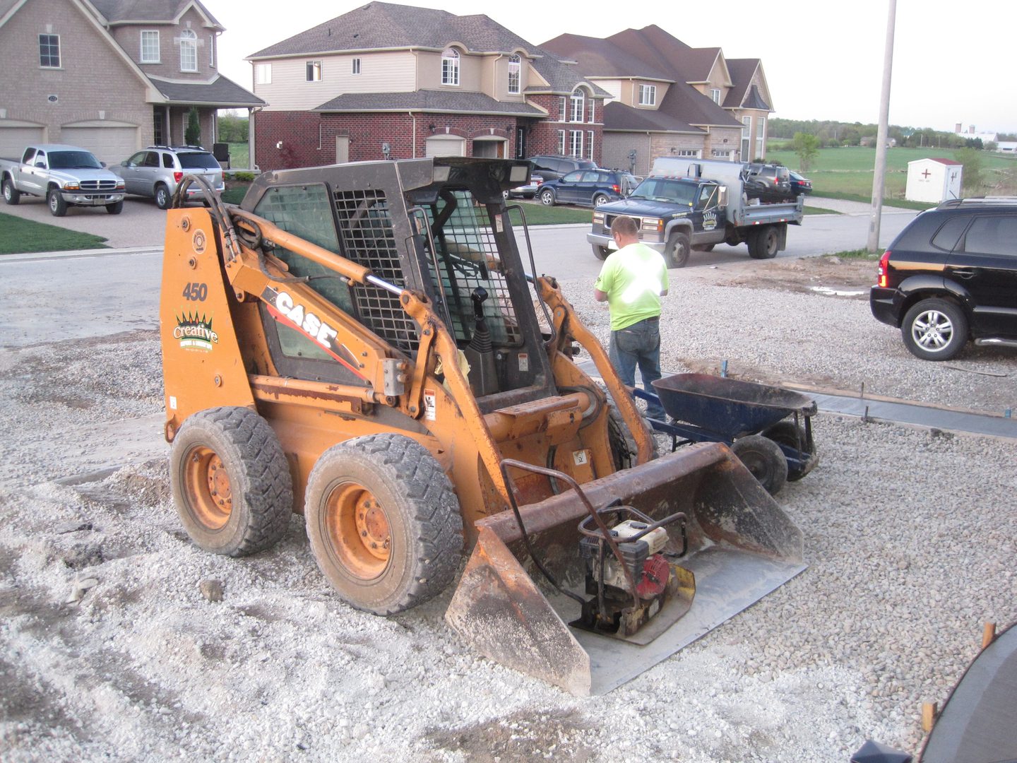 A man standing next to an orange and black tractor.