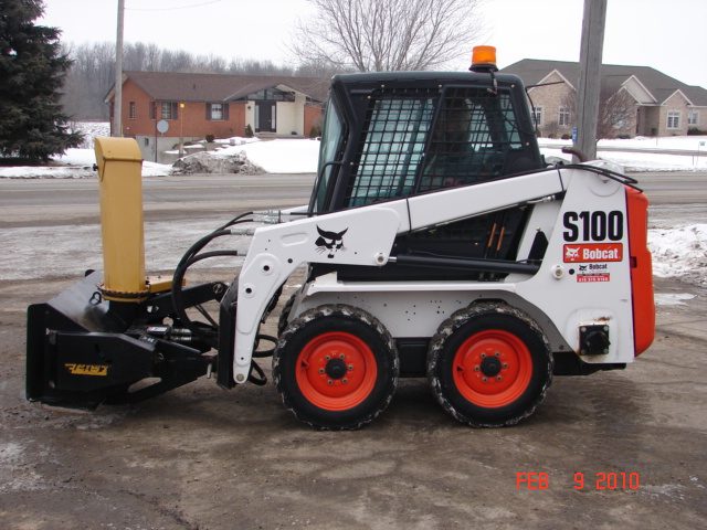 A small white and black tractor is parked in the snow